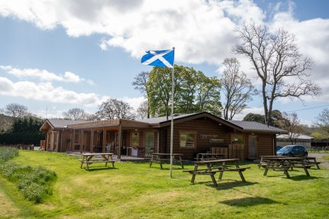 an outside photo of the Waterwheel tearoom with picnic benches and a scotland flag flying